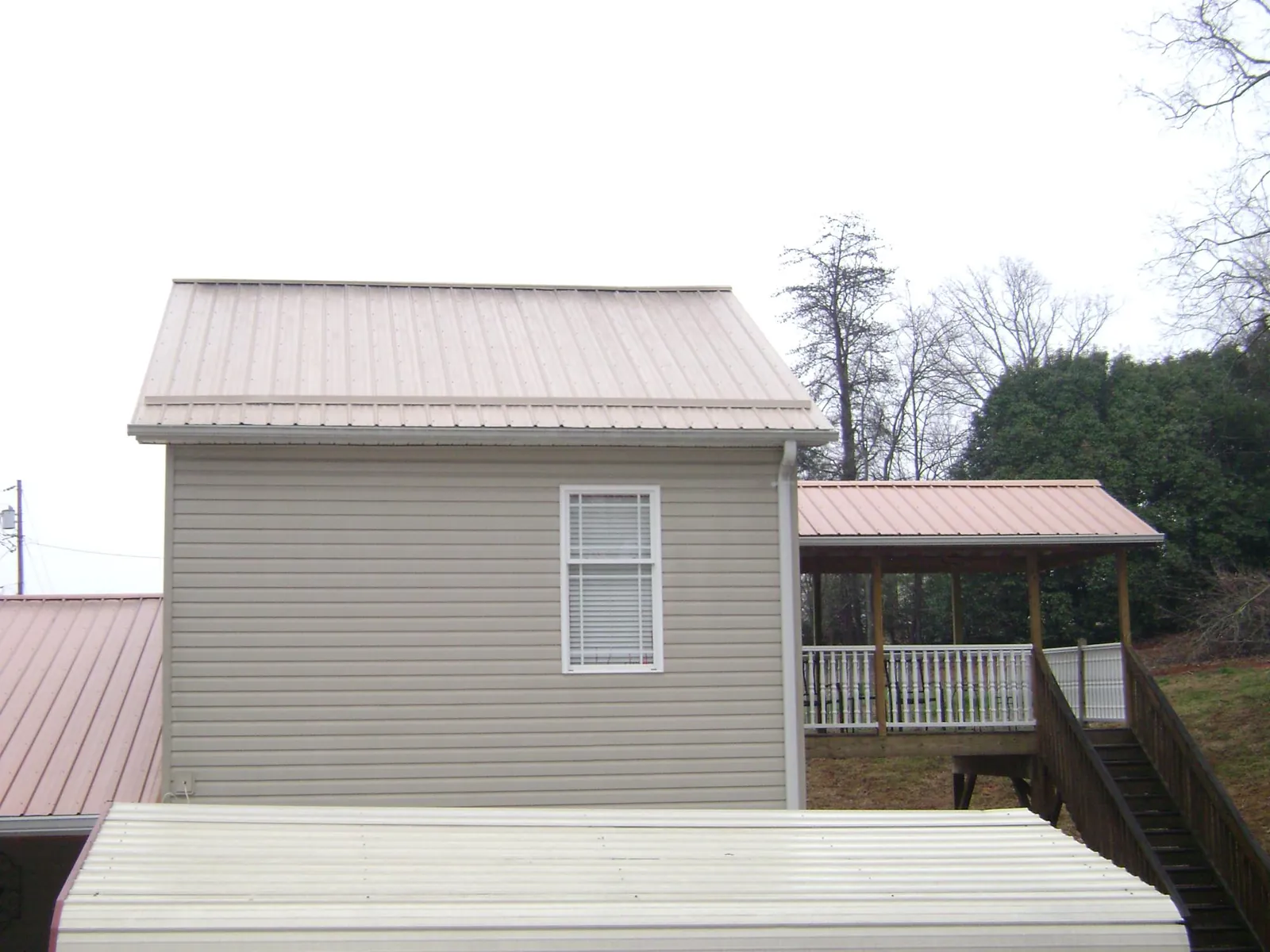 Tan metal roofs on a two story addition and attached porch, from a Roof Replacement job in Sherwood
