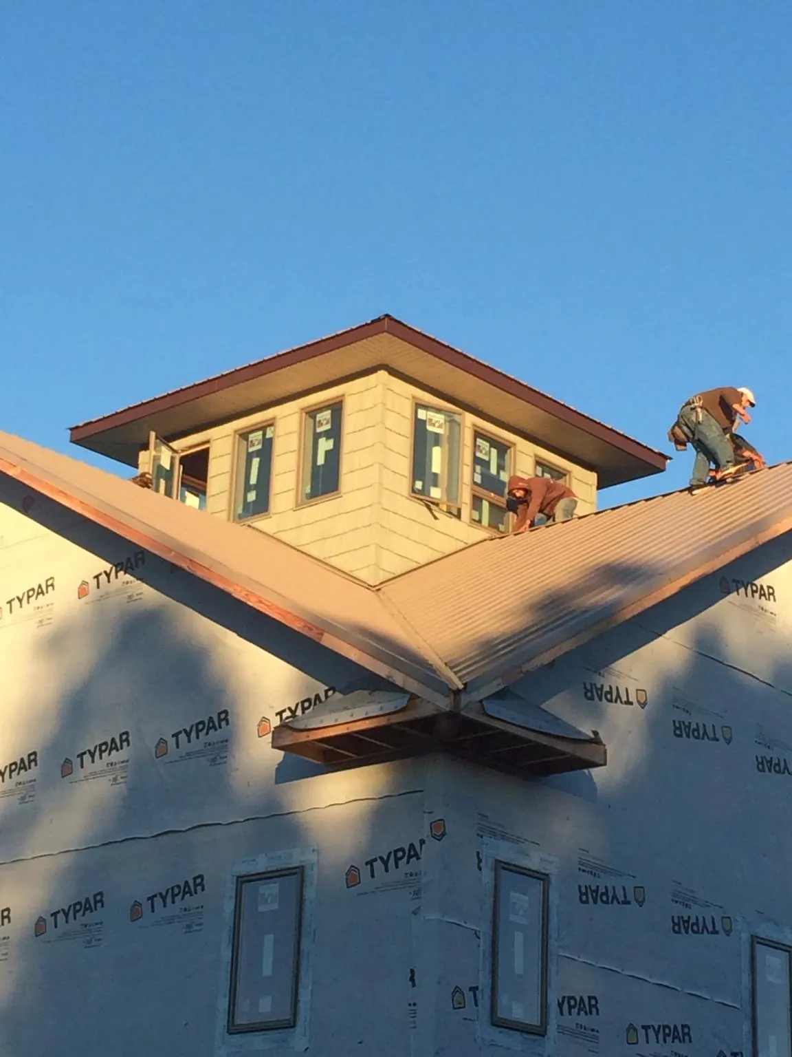 Roofers working around a rooftop cupola on a new metal roof at sunset — Roof Waterproofing in Sherwood by Roofing Brothers
